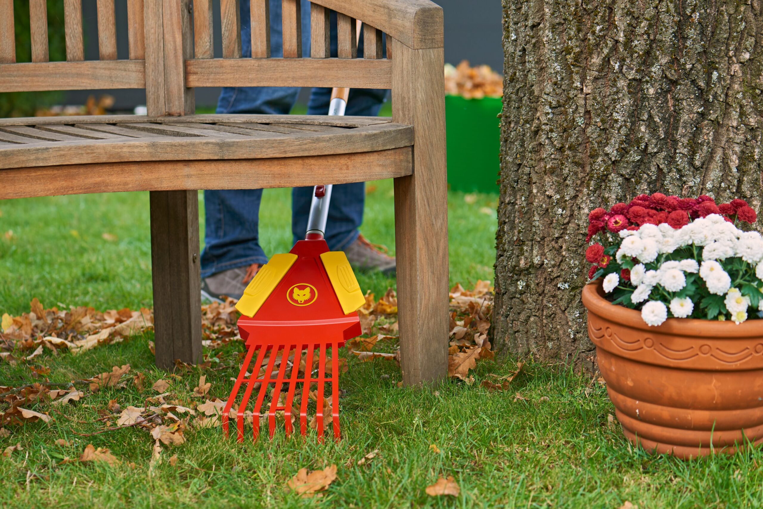 Ein Mann sammelt Herbstlaub mit dem WOLF-Garten Multi-Star® Systemaufsatz LEAF RAKE 4-IN-1.